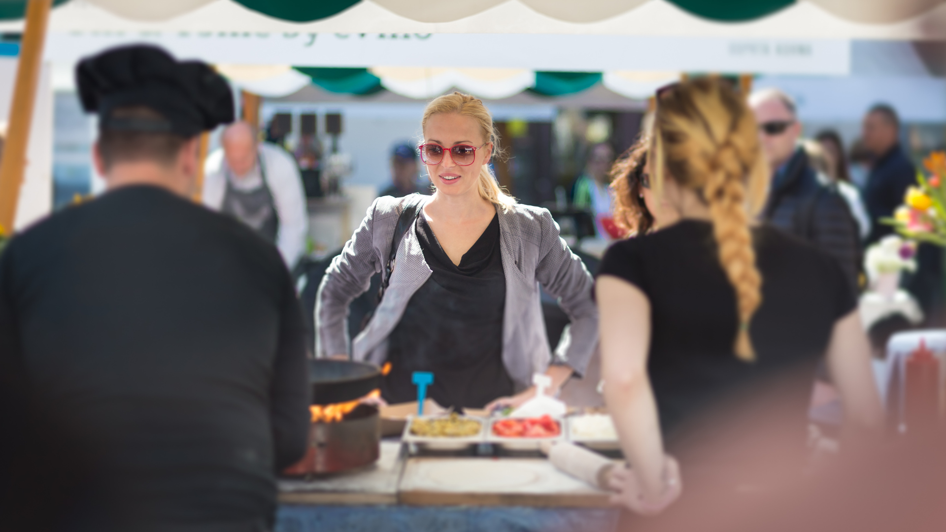 Woman ordering food from street market vendors at outdoor stall