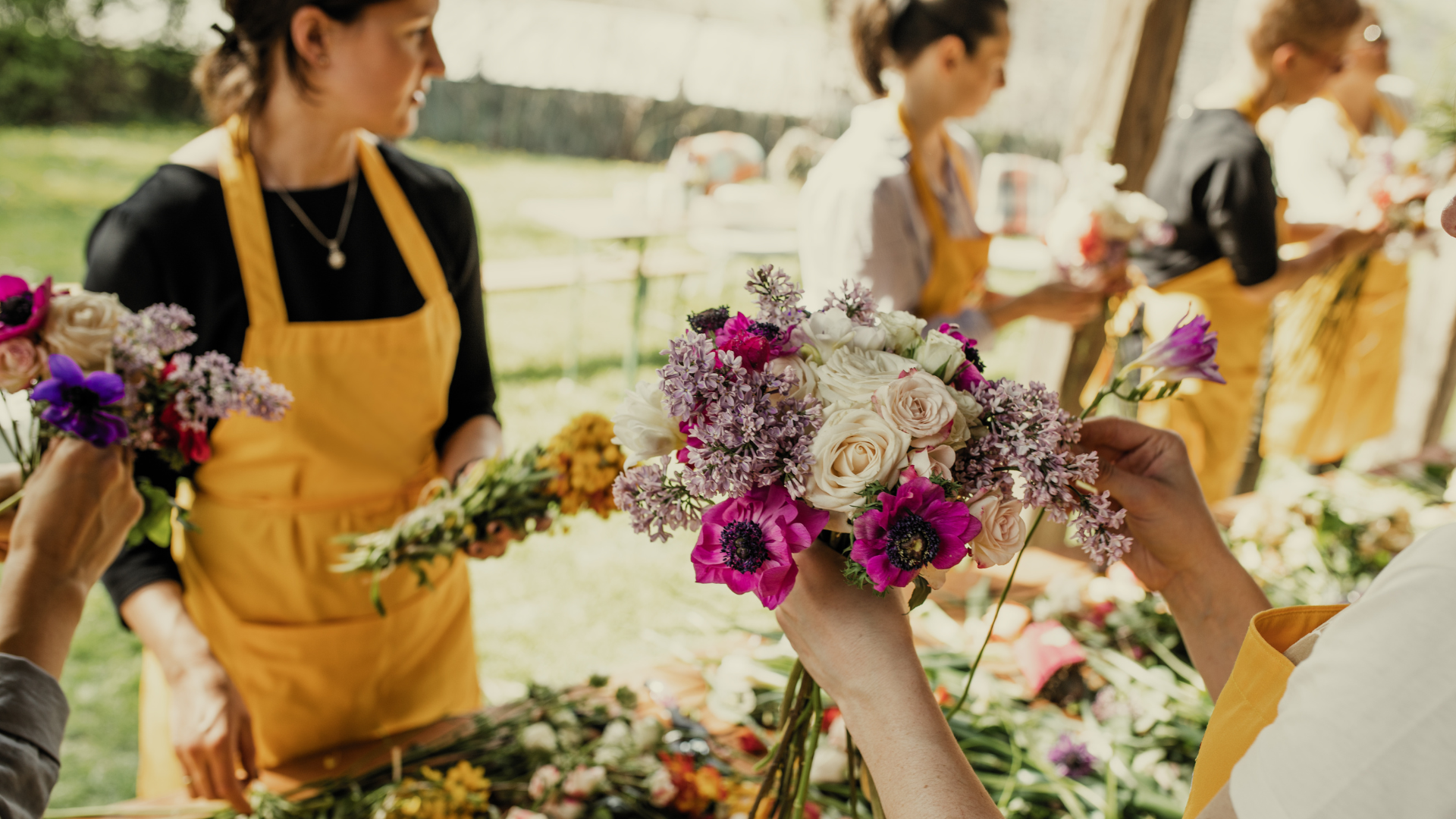 Florists arranging colorful flower bouquets at outdoor workshop